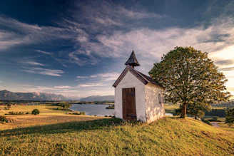 A rustic chapel surrounded by fields at sunset.