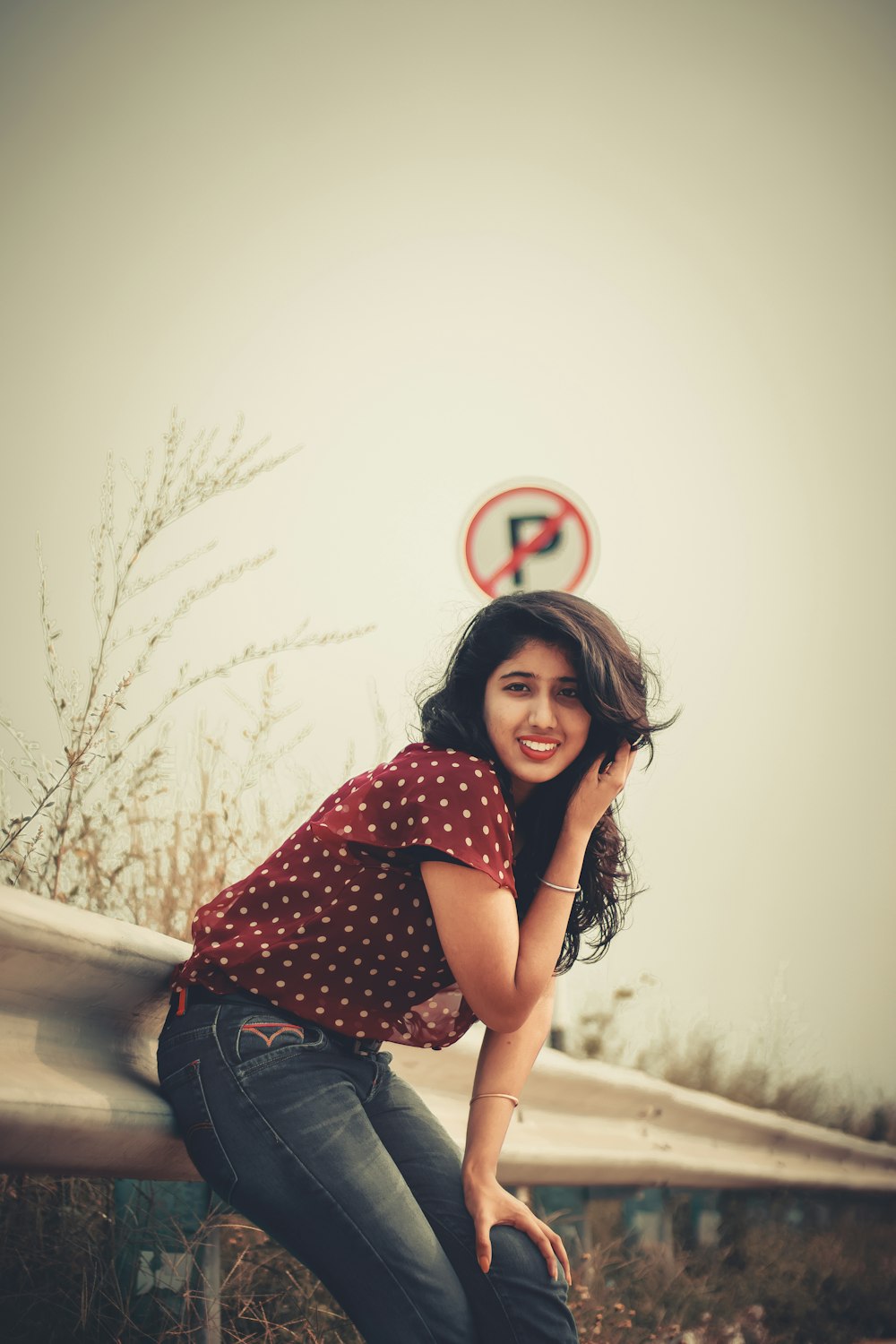 woman wearing red blouse leaning on white metal fence