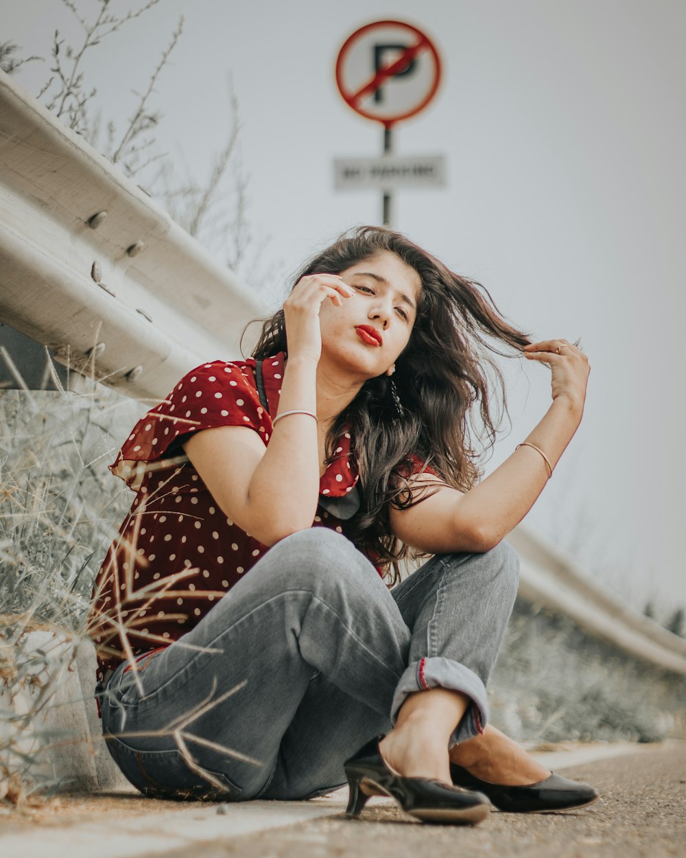 woman sitting beside No Parking sign