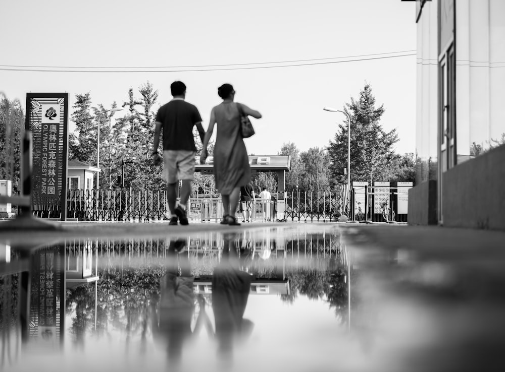 greyscale photo of two people walking on street