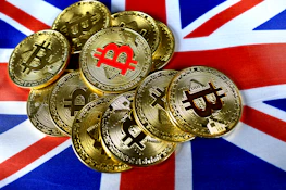 Several gold-colored Bitcoin coins with the Bitcoin symbol are scattered over a vibrant British flag, creating a contrast between the digital currency and national symbol.