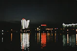 Nighttime shot of Dubai's illuminated towers reflecting on the calm waters of the bay.