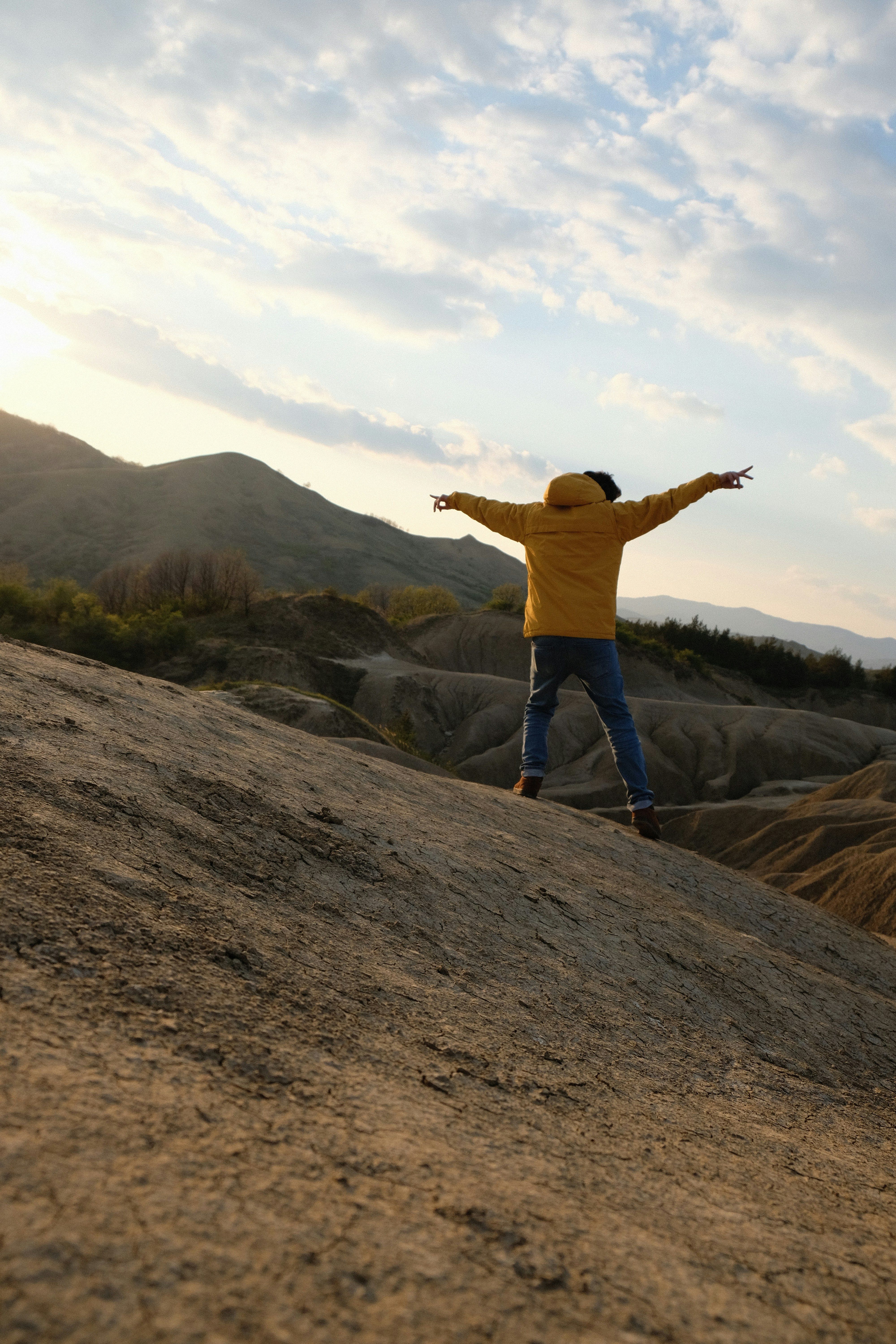 person in yellow hoodie standing on mountain during daytime