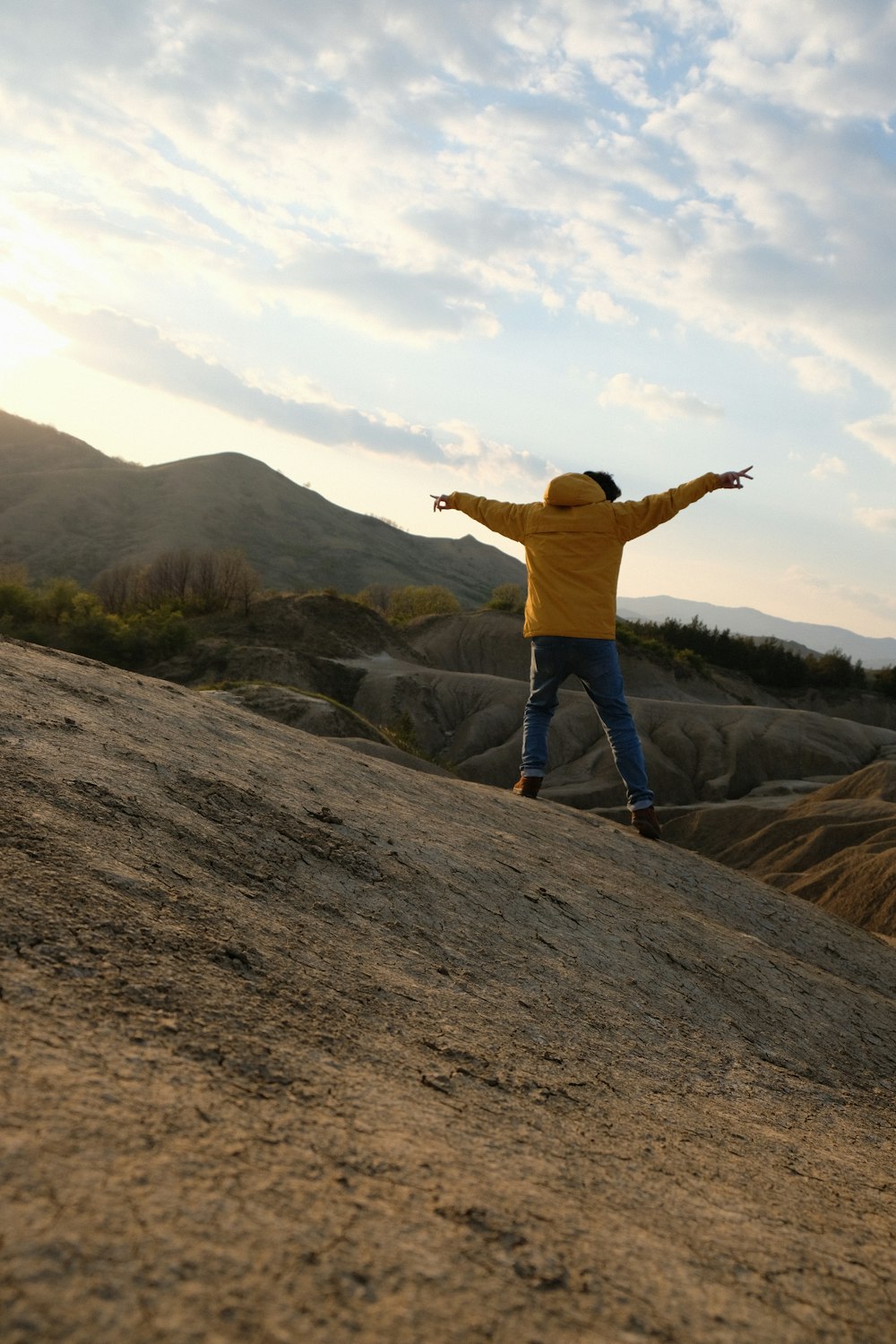 person in yellow hoodie standing on mountain during daytime