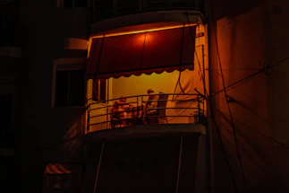 A cozy Rome apartment balcony with warm evening light and a small table set for two.