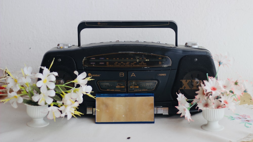 black boombox beside two potted flower arrangements