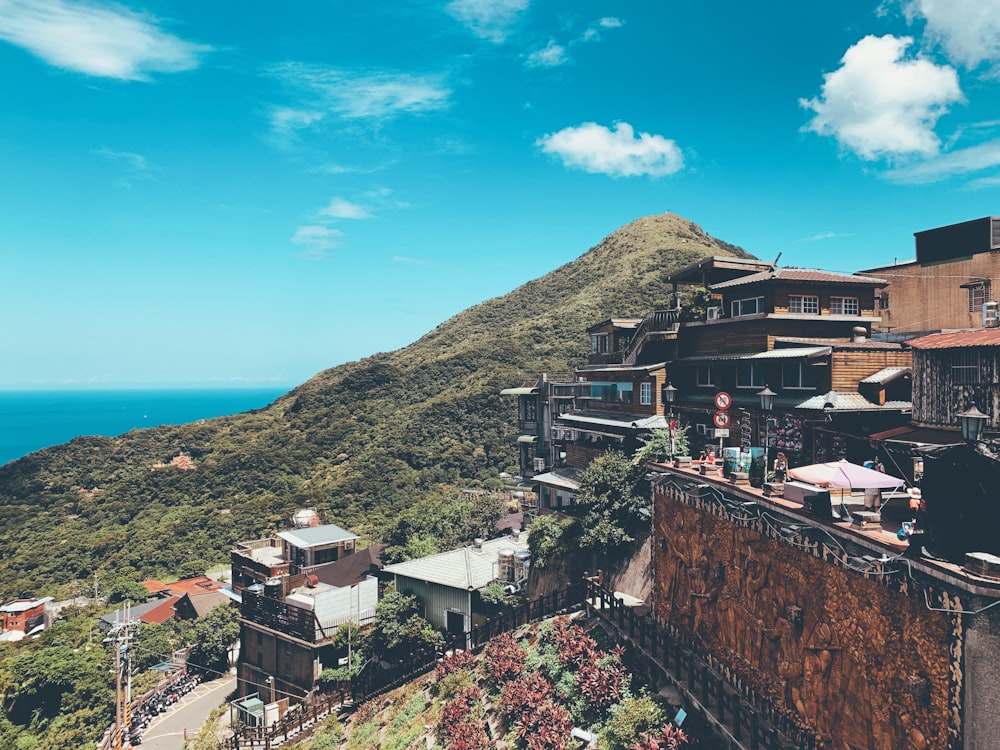 houses near mountain under blue and white skies during daytime