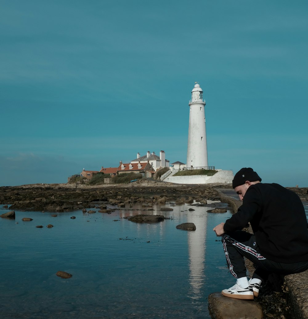 man sitting near lighthouse