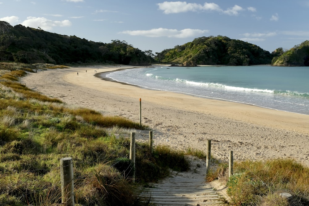 seashore viewing calm sea and mountain under blue and white skies during daytime