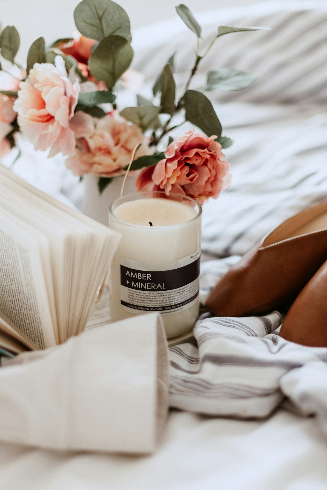 Amber Mineral votive candle near open book and peonies