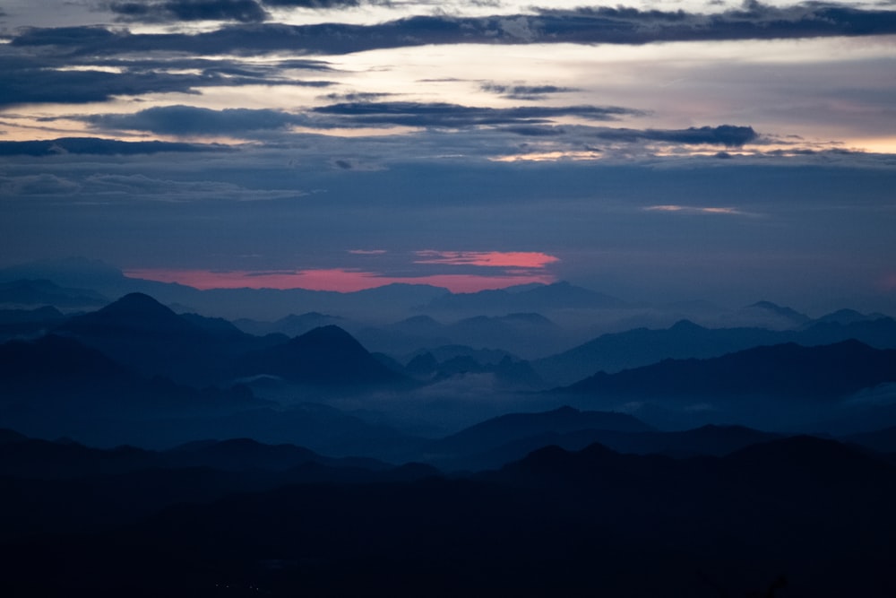 silhouette of mountains under cloudy sky