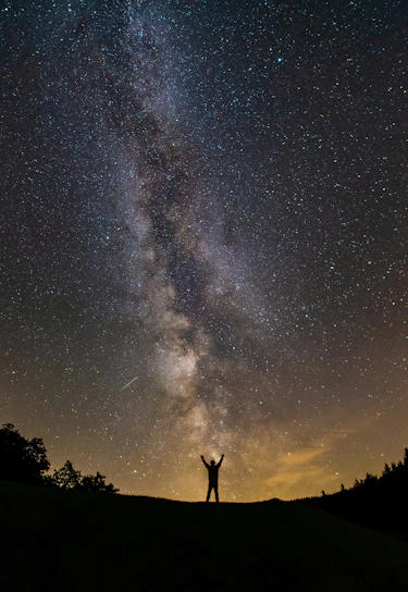 A glowing silhouette of a woman standing tall under a starry sky, embodying strength and grace.