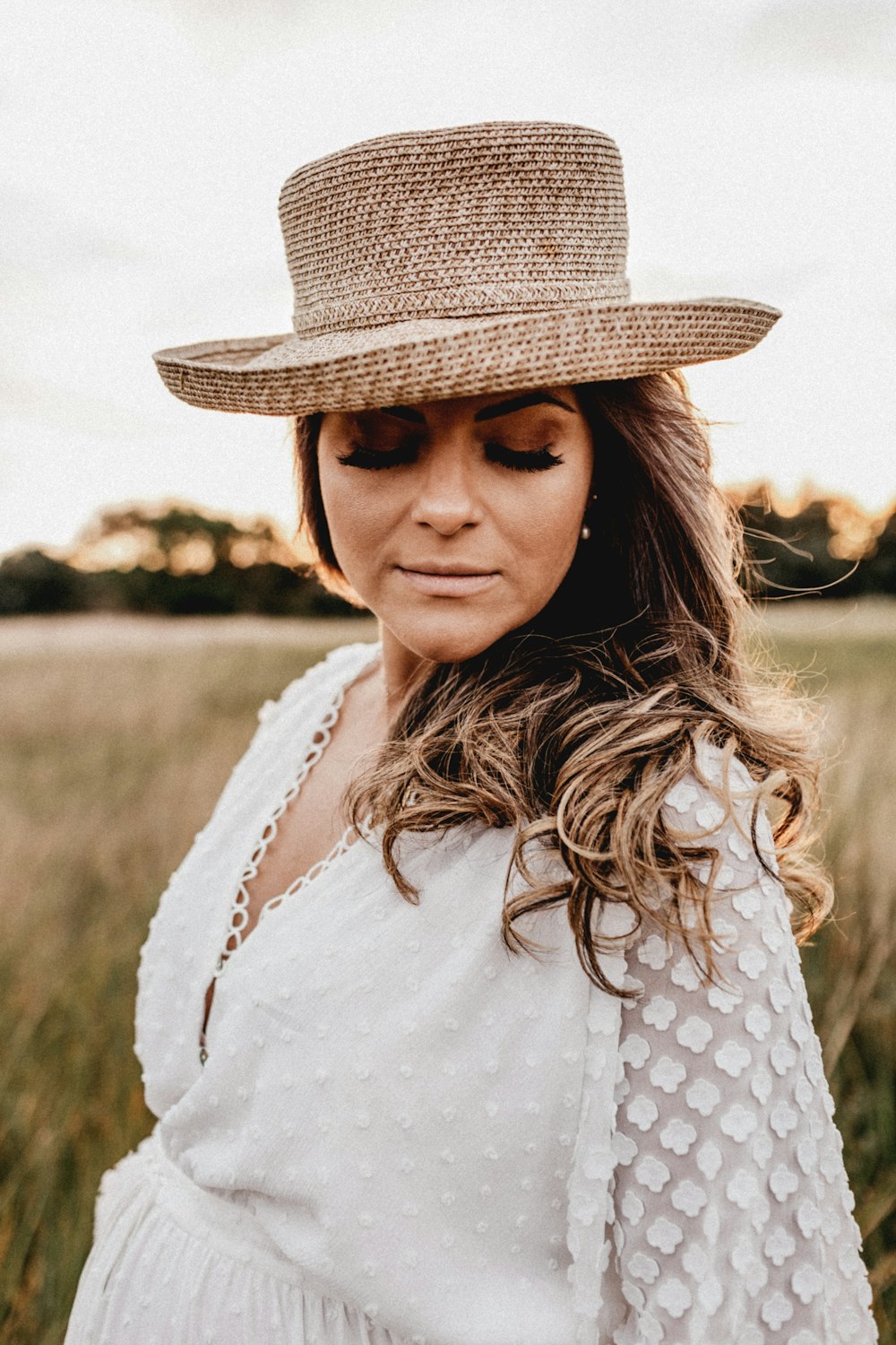 a woman standing in a field wearing a hat
