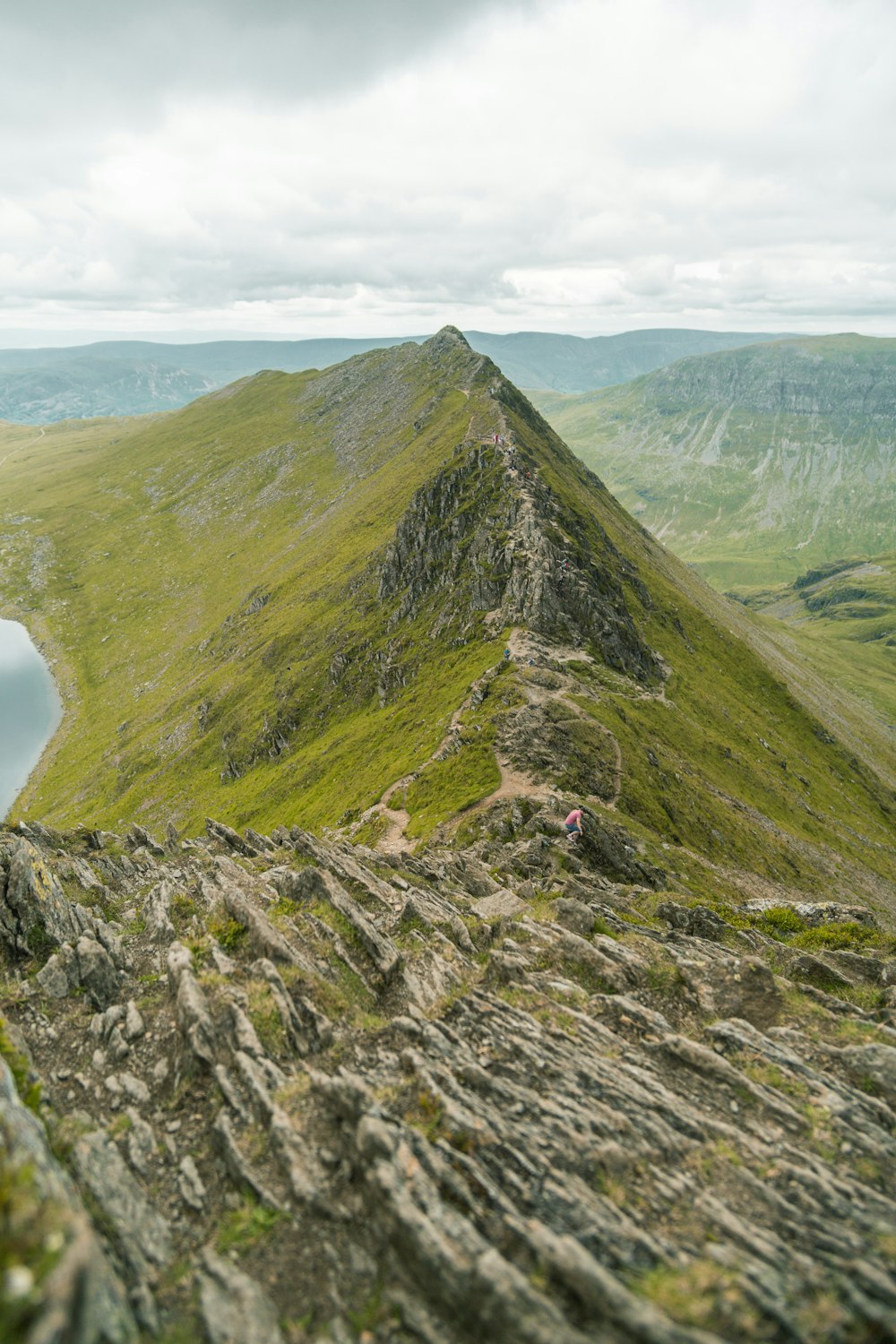 Un uomo in piedi sulla cima di una montagna vicino a un lago