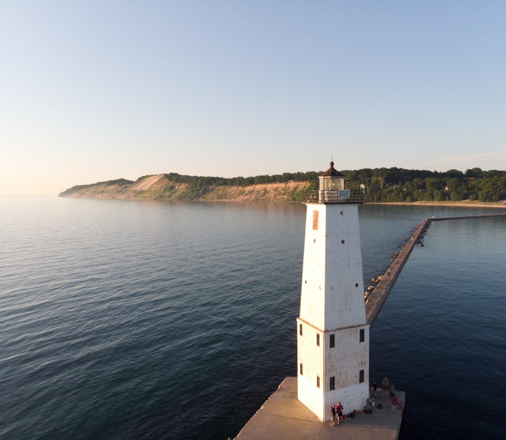 people near white lighthouse tower