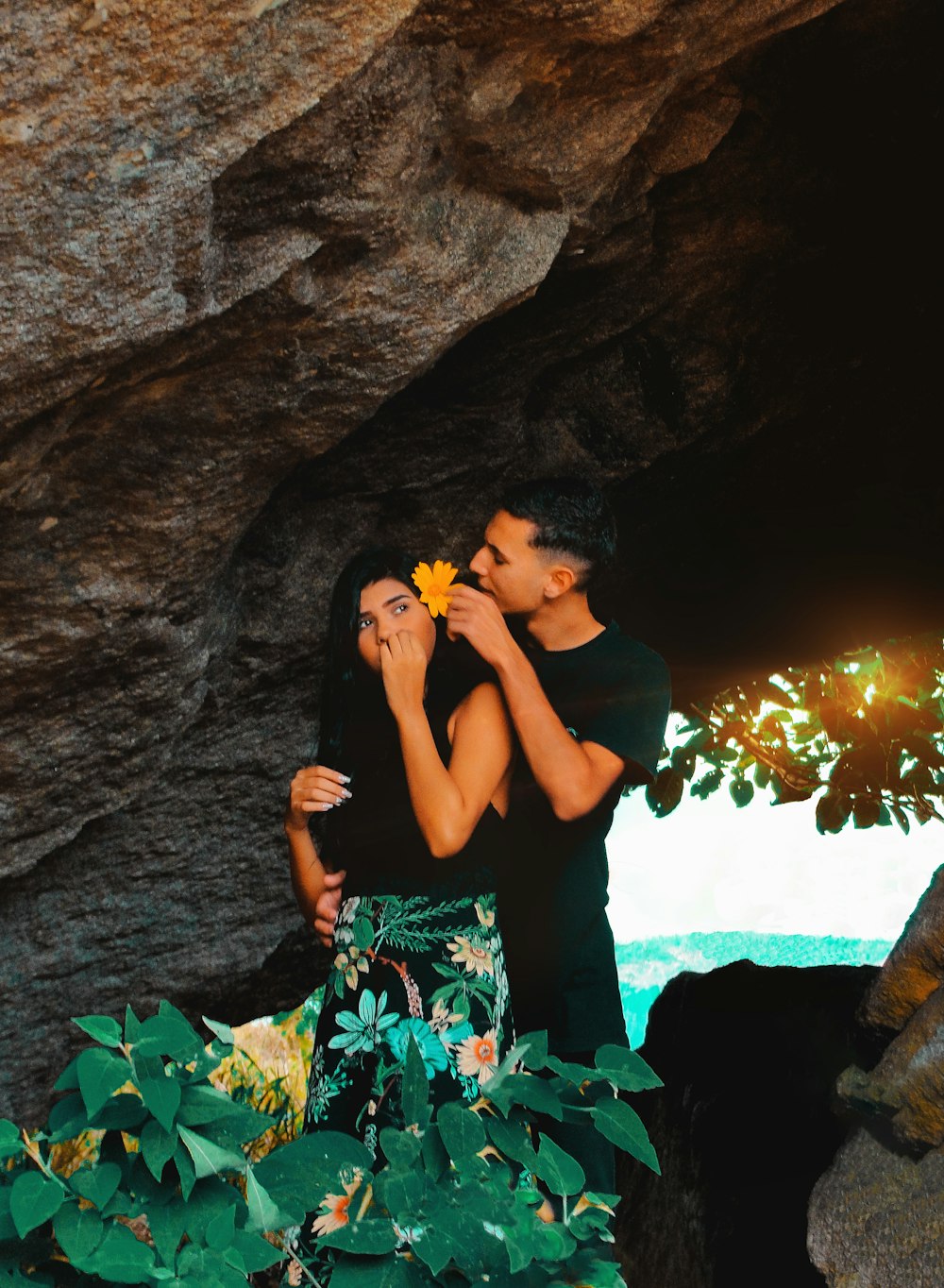 man placing yellow flower on woman's ear