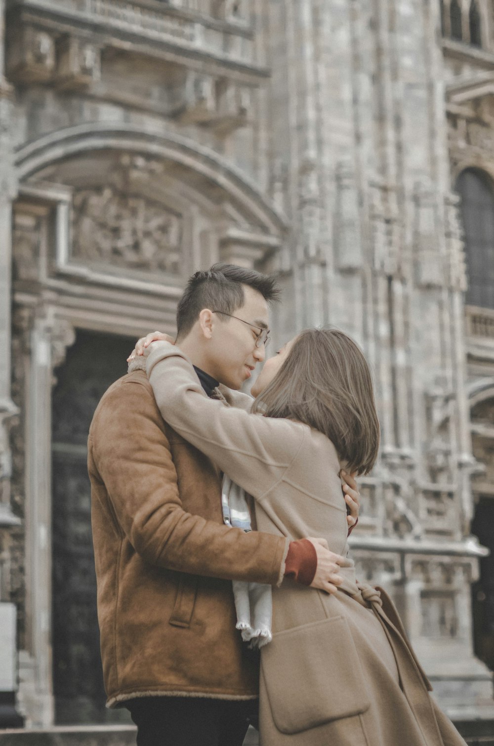 man and woman kissing front of building