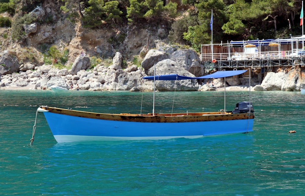 boat floating on body of water near rocky shore