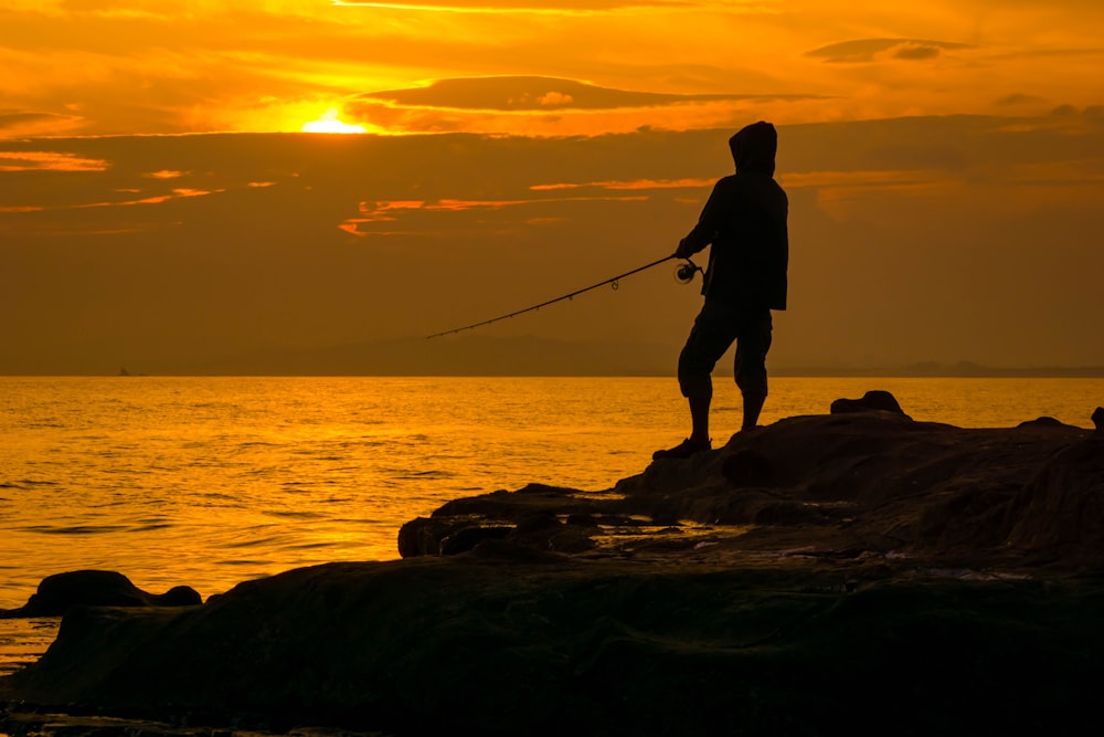 silhouette di persona che tiene la canna da pesca