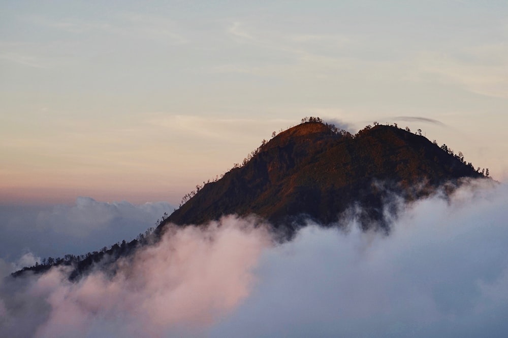 brown mountain surrounded by white clouds at daytime