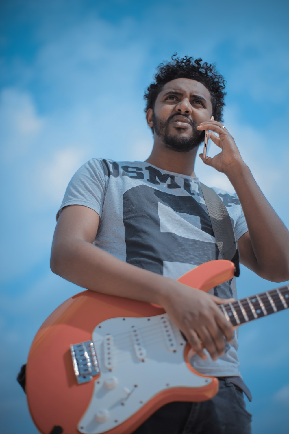 man holding ink and white electric guitar close-up photography