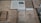 Several old books and documents are laid out on display, including a map and a book open to a black-and-white photograph of several people. The texts appear to be in Russian, suggesting historical or cultural content. The materials seem aged, with some wear and discoloration, hinting at their historical significance.