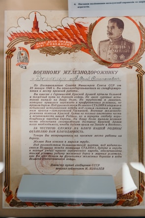 A formal Soviet certificate with Cyrillic text, featuring an image of a decorated military officer, likely a leader from the USSR era. The certificate includes red and gold patriotic themes with flags and symbols, and praises a railway worker for his dedicated service.