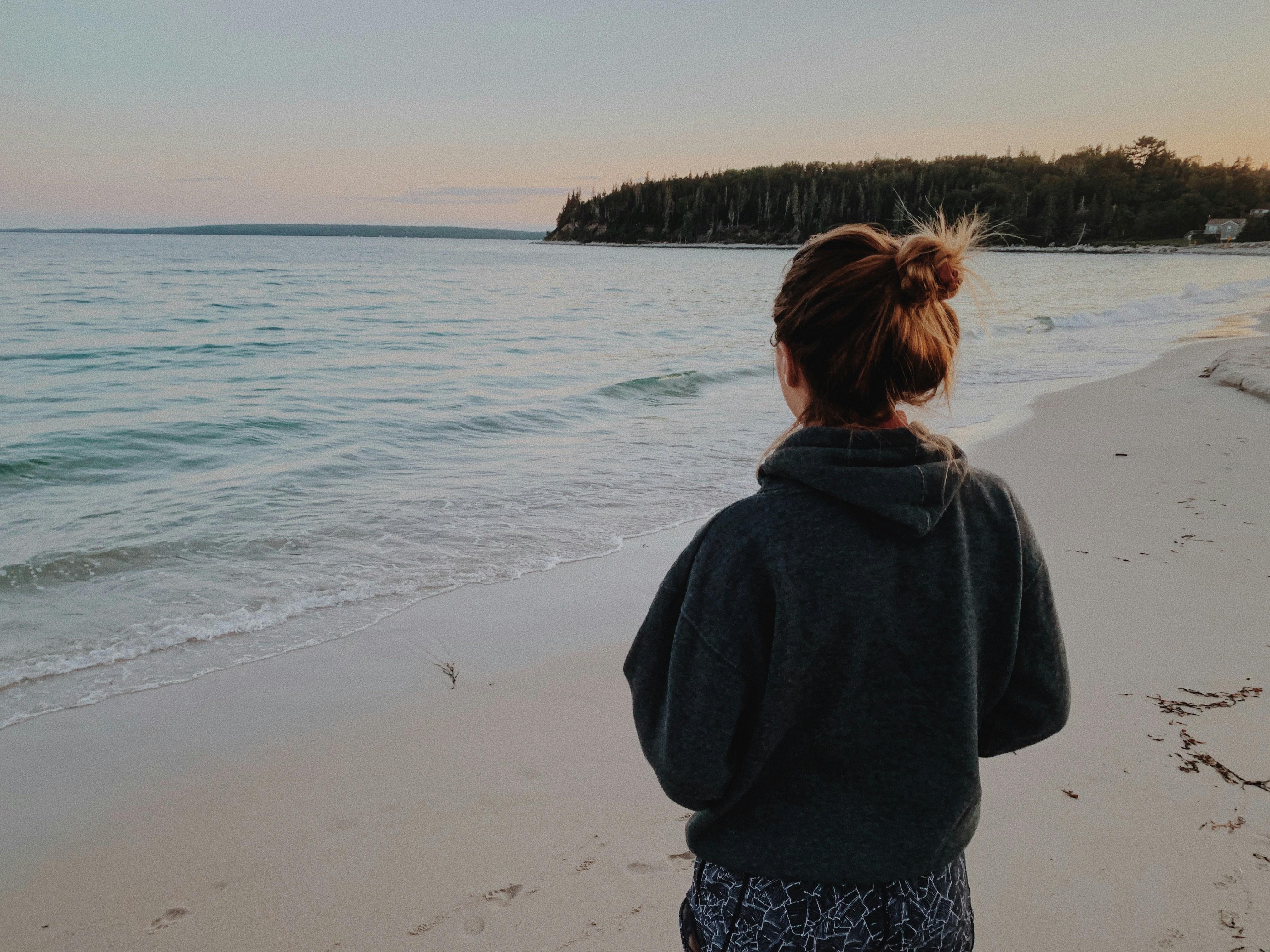 woman standing on the seashore, sunset in august