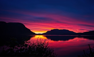 A stunning sunset over a calm lake reflecting the sky.