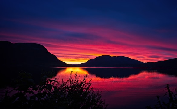 A beautiful landscape with a stunning sunset over a calm lake.