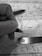 A monochrome image depicting a close-up of a hand holding a pen over a map. A ruler is also placed on the map, indicating measurements or planning activity. The map details roads and locations, with 'Paris' marked prominently.