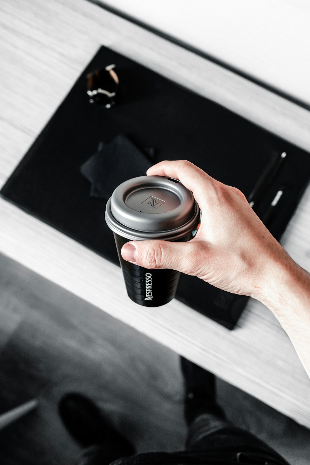 person holding black Nescafe coffee cup with lid