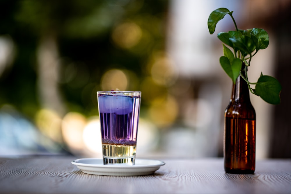 clear shot glass beside amber glass bottle