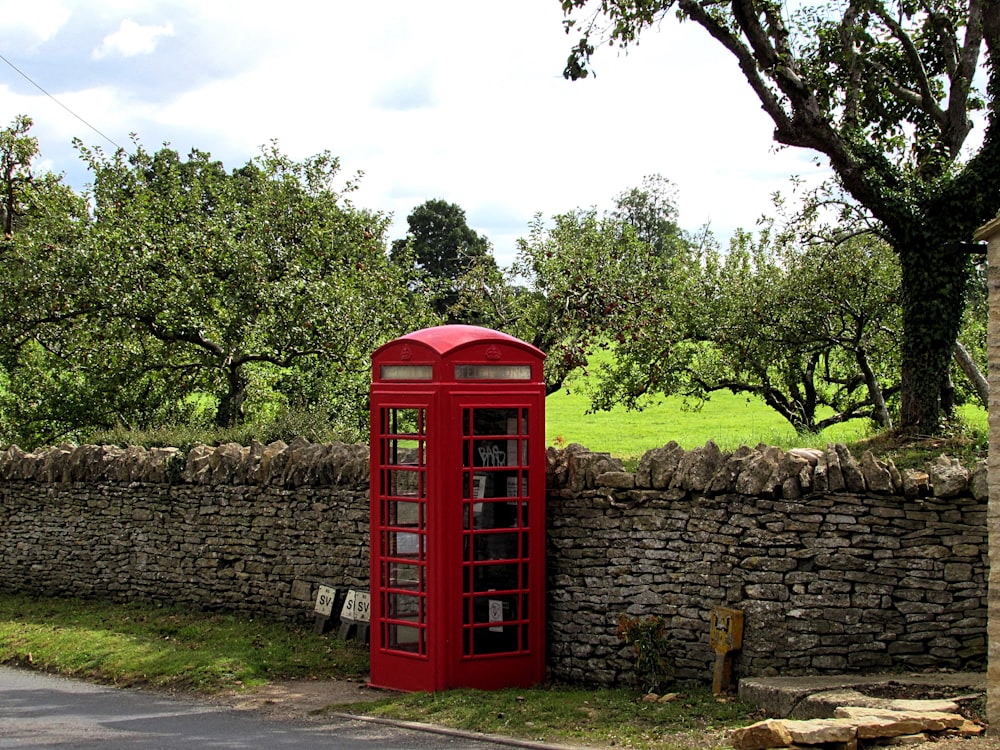 red telephone booth beside brick wall