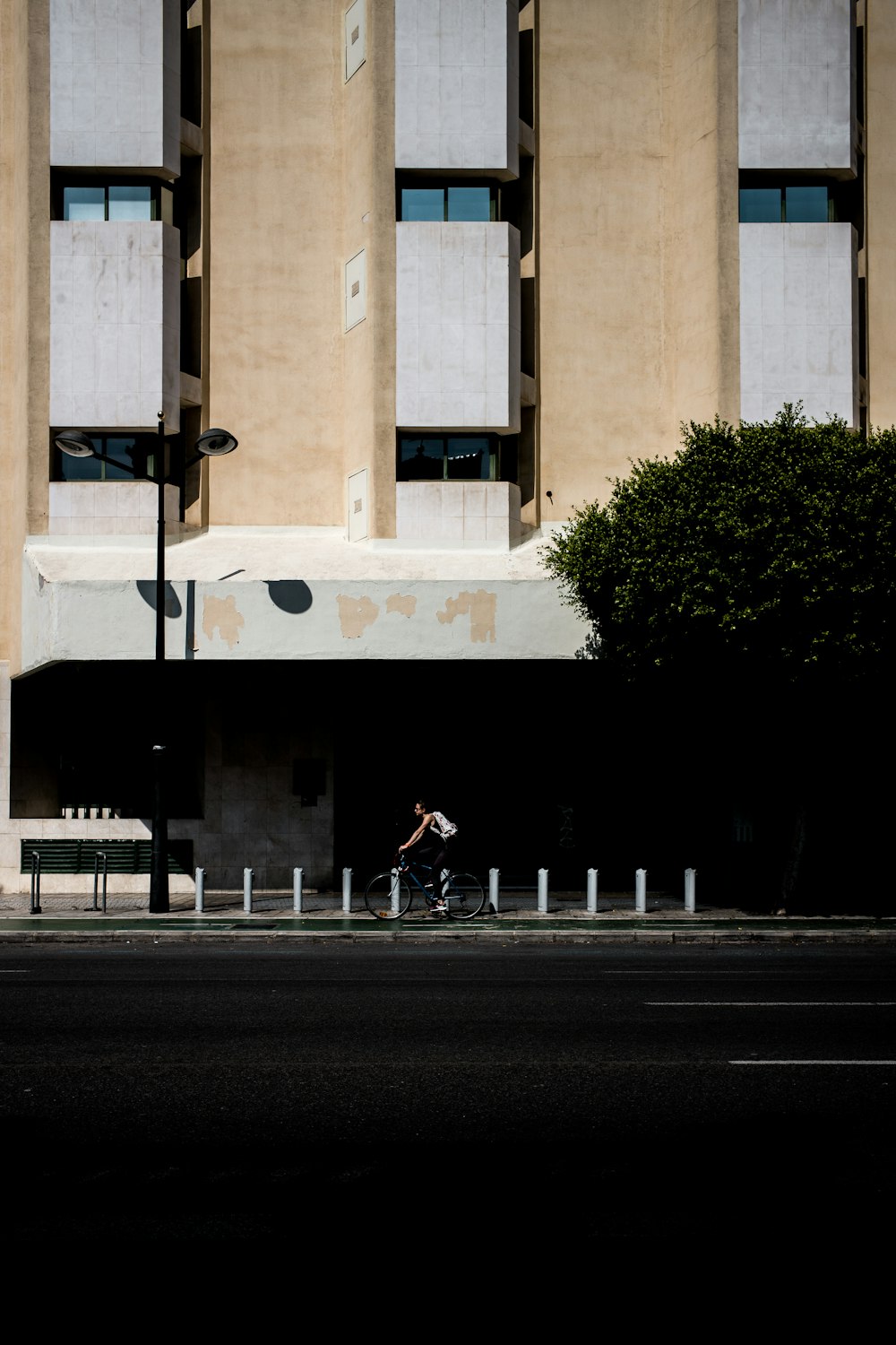 hombre montando en bicicleta al lado de un edificio de hormigón