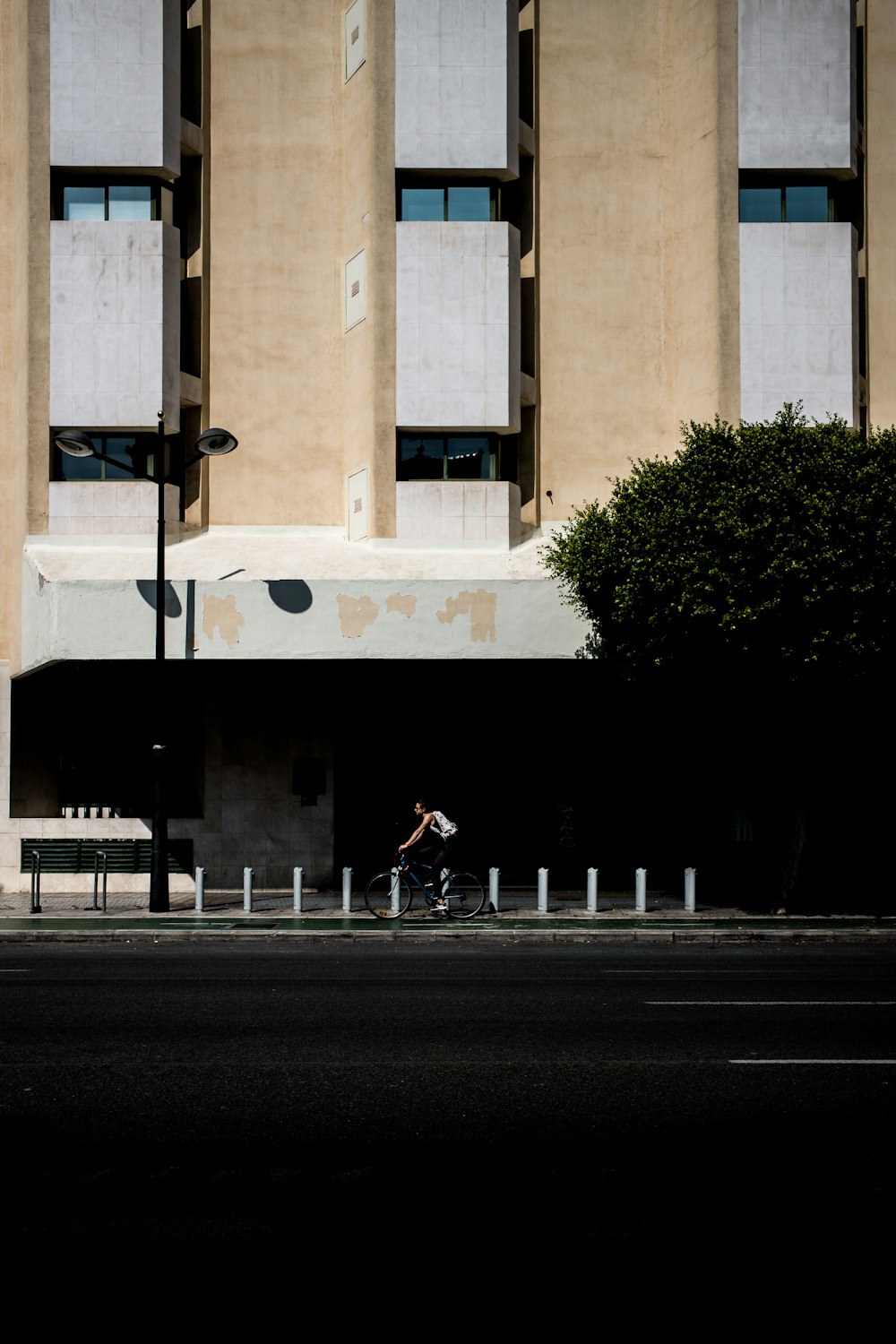 man riding on bicycle beside concrete building