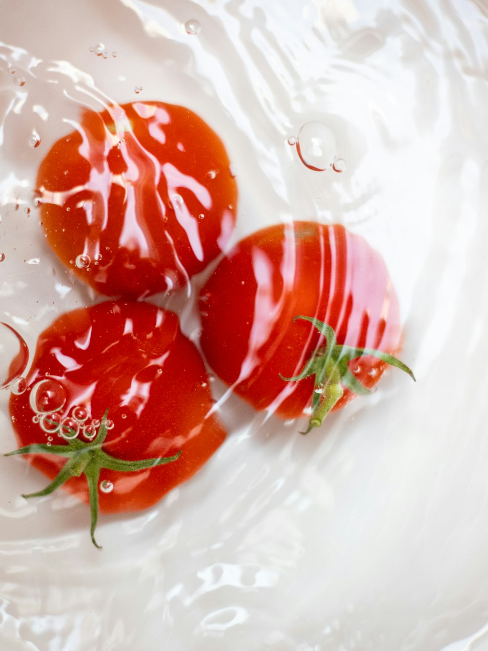 three red tomatoes in water