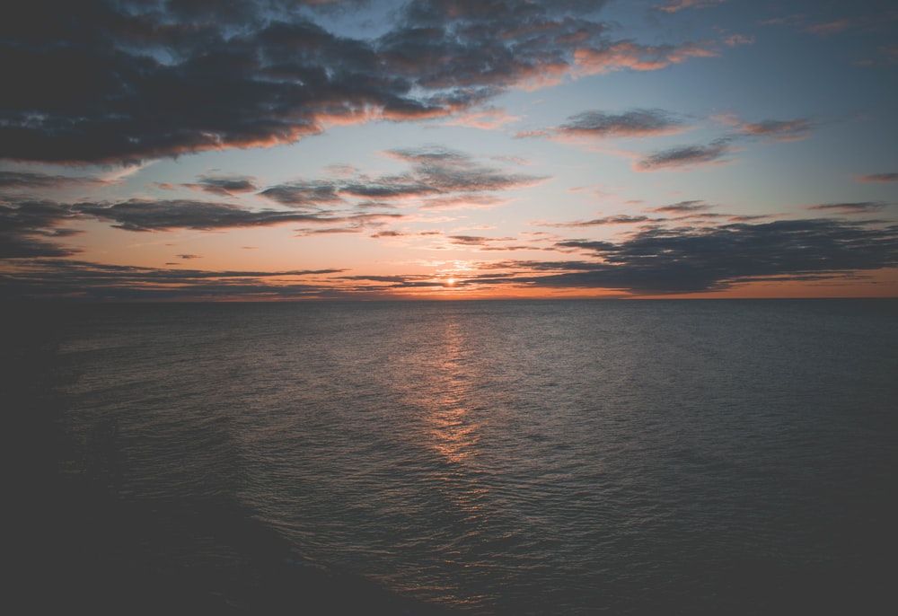 sea under cloudy sky during golden hour