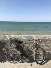 Vintage bicycle resting against a weathered stone wall near the sandy Adriatic coast under soft natural light.