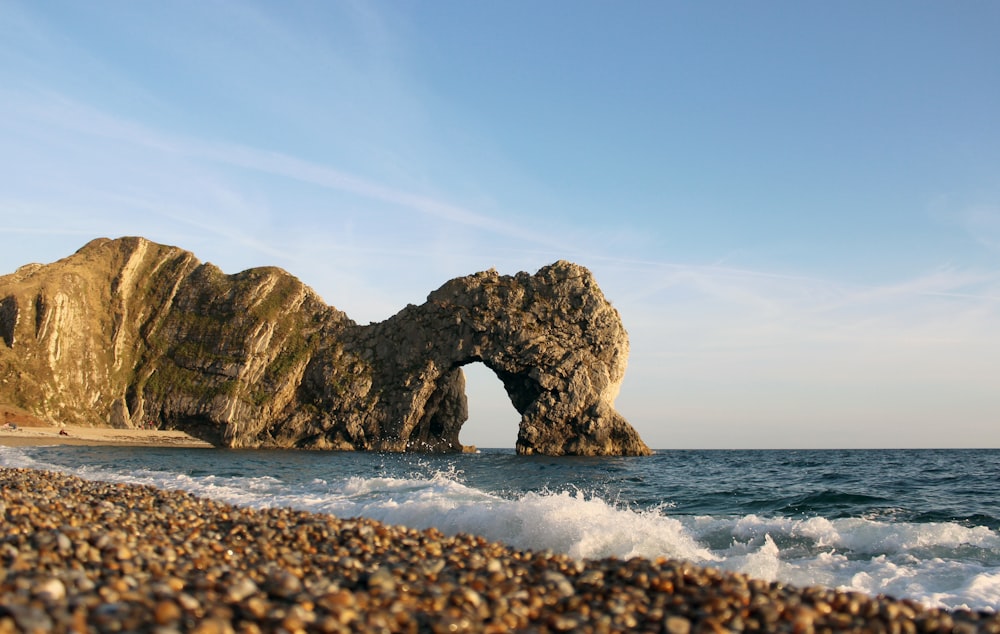 arch rock formation in sea under blue sky