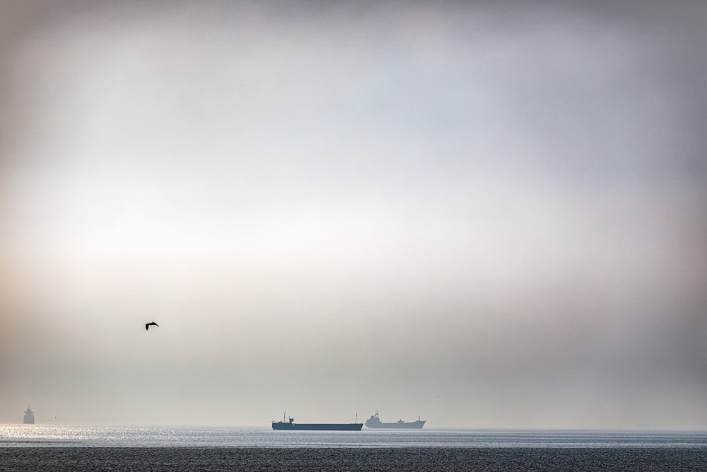 silhueta de barcos à vela sob o céu cinzento durante o dia