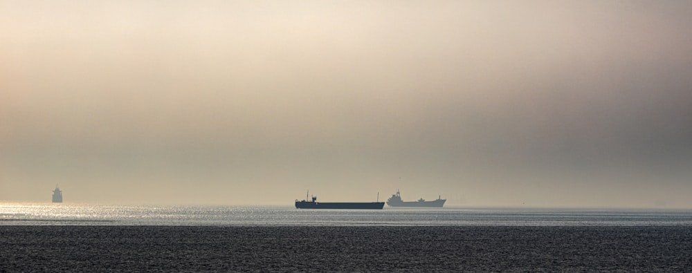 昼間の海上に浮かぶ黒と灰色の2隻の船