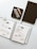 A well-organized flat lay featuring an open planner filled with handwritten notes and stickers. Next to the planner is a black notebook, a decorative bundle of sage, and a bronze-colored pen, all neatly arranged on a small black tray.