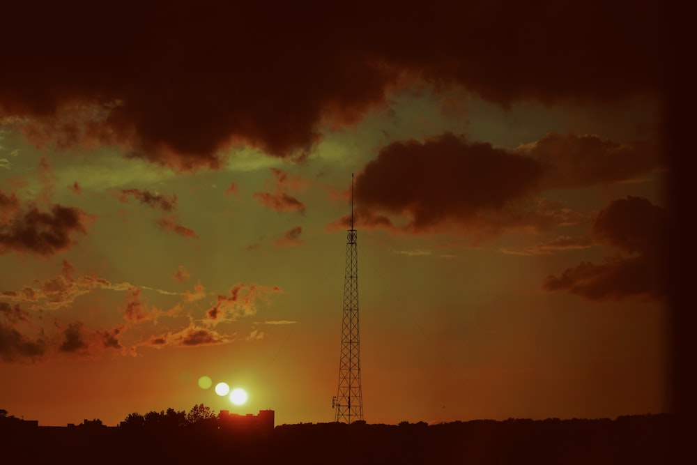 the sun is setting behind a radio tower