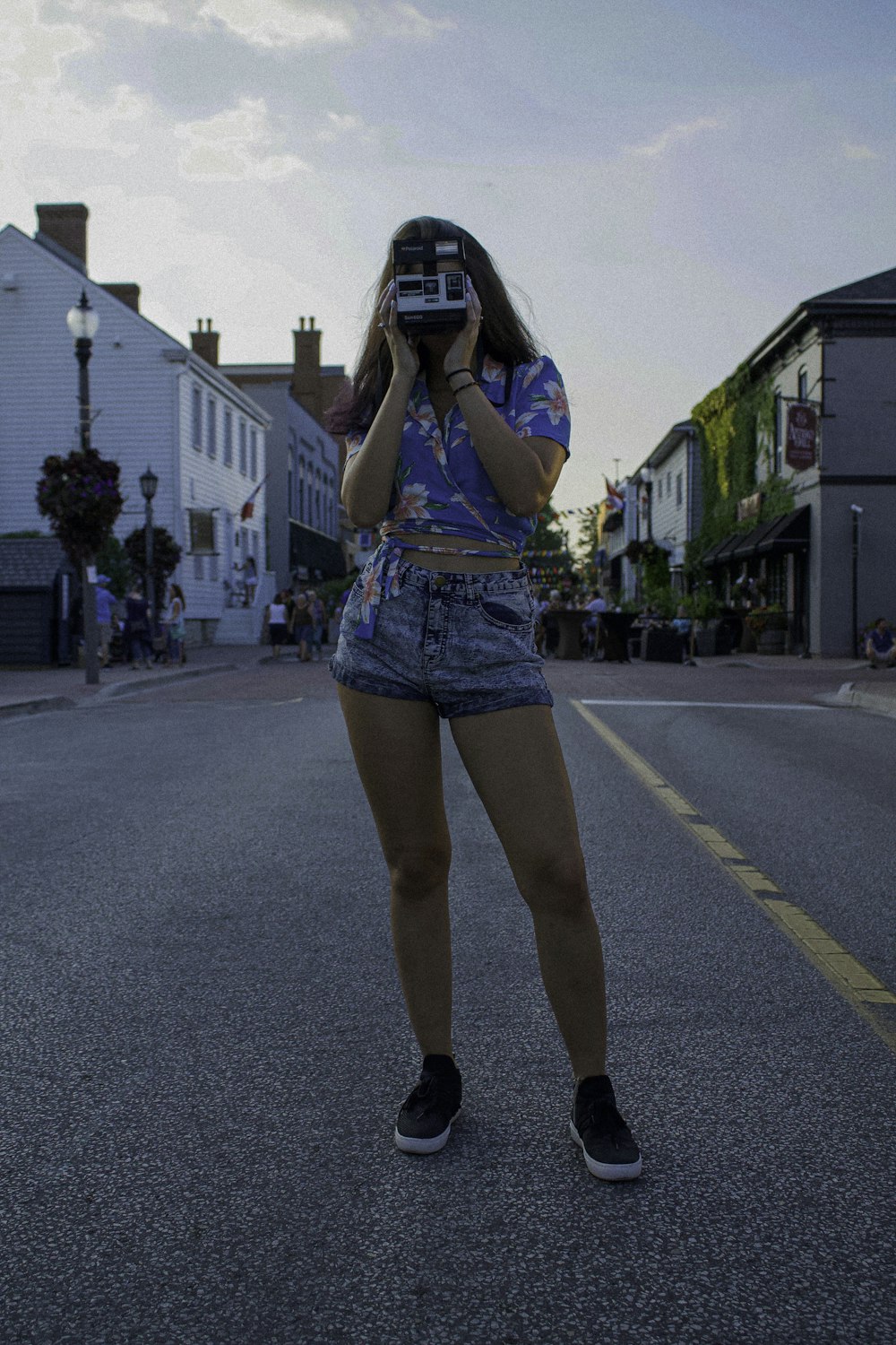 femme debout sur la route à l’aide d’un appareil photo