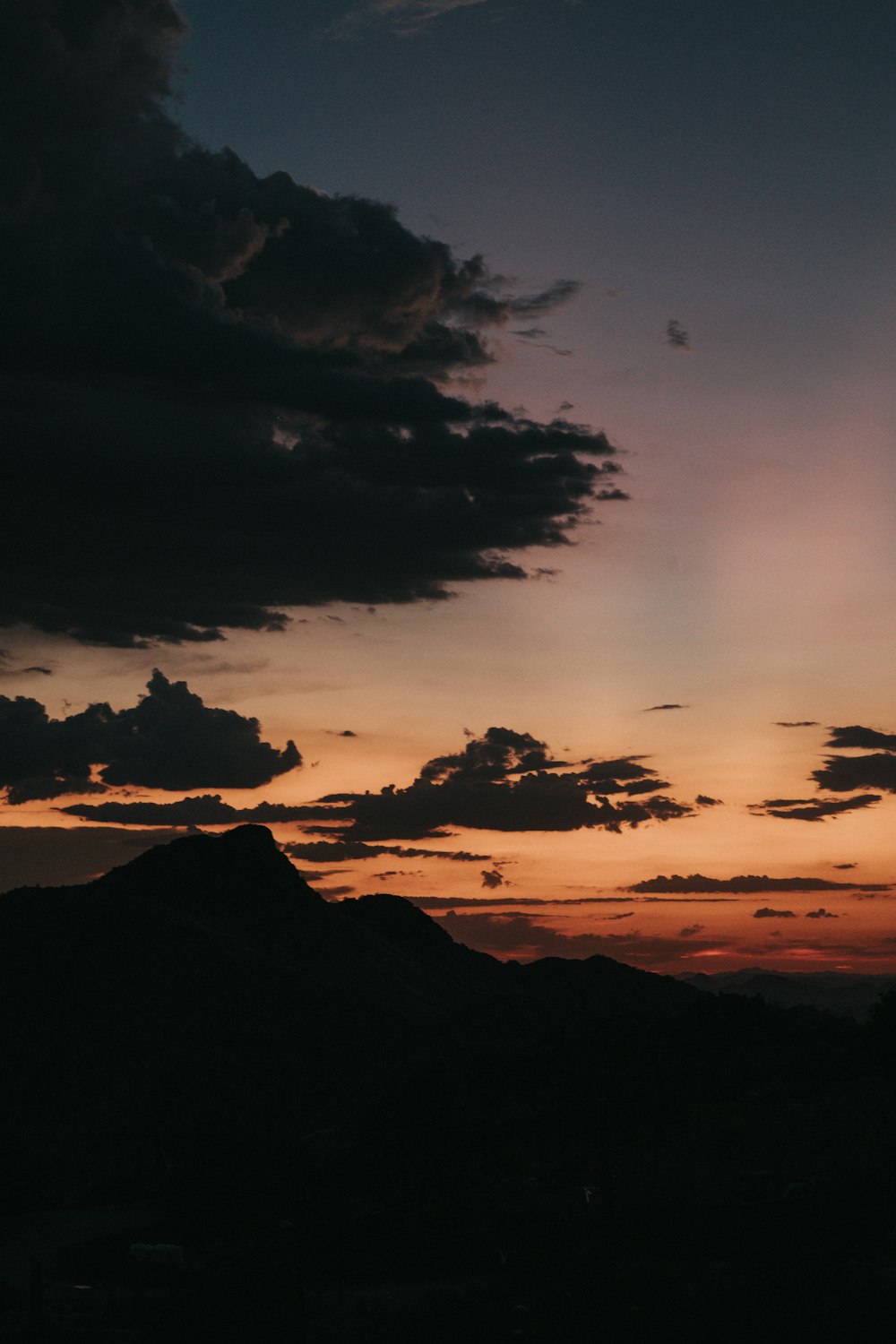 silhouette of mountains under cloudy sky