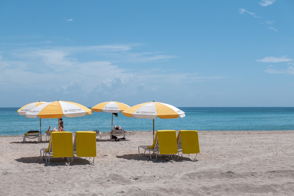 four white-and-yellow off-set umbrellas on seashore during daytim