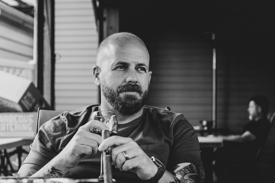 grayscale photography of man sitting front of table