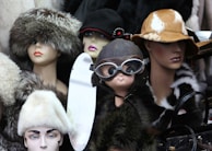 A display of trendy hats and caps arranged on mannequin heads.