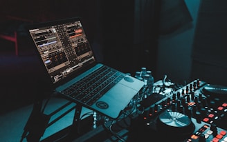 a laptop computer sitting on top of a mixing desk